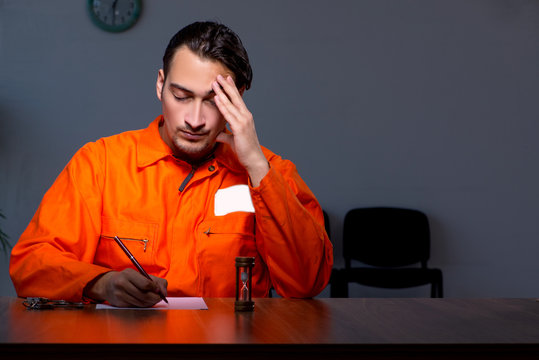 Young convict man sitting in dark room