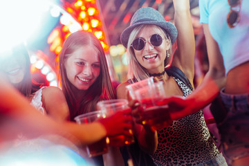 Close up of the girls toasting with beer in the club