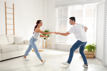 Fototapeta na wymiar Beautiful young couple dancing in living room