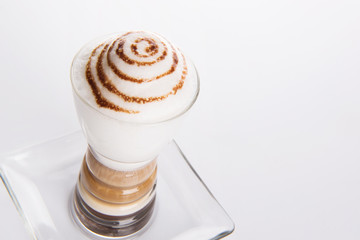 a delicious latte macchiato with cocoa sprinkled in a glass cup on white background