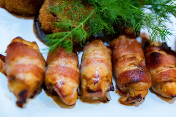 Plate with freshly cooked bacon rolls close up