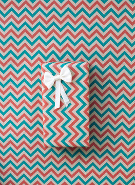 Christmas gift in a zig zag wrap on a same pattern background