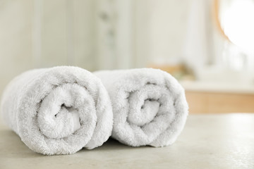 Fototapeta na wymiar Clean rolled towels on table in bathroom