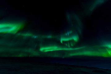 Aurora borealis in night northern sky. Ionization of air particles in the upper atmosphere.