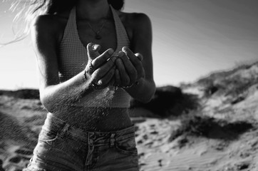 Greyscale shot of the sand sliding through the palms of a female