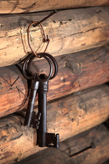 Two antique large metal keys hang on the wooden wall. Macro photo in the interior.