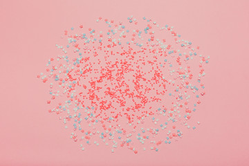 Colorful small candies on the pink background.