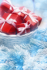 Close up of Christmas composition with red gift boxes in basket and frosty branches. New Year and Xmas concept
