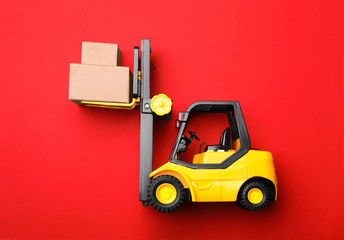 Top view of toy forklift with boxes on red background. Logistics and wholesale concept