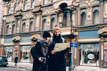 Sweet couple of tourists smiling while looking on map
