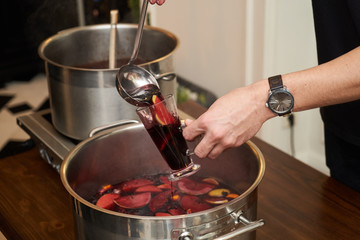 Man pours fruit compote into a glass, close-up. Healthy compote