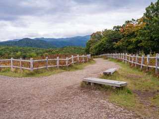 Two benches by a path in Shiretoko National Park, under a cloudy sky.