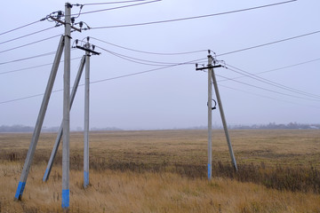 Landscape. The poles of power lines in the field in the autumn foggy morning.