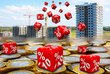 Discounts on the purchase of apartments in new buildings. Red cubes with discounts fall to the surface of Russian coins on background of high-rise apartment buildings under construction