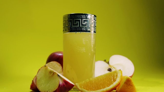 a glass of lemon juice with fruit on a yellow background