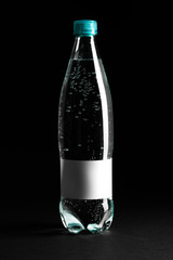 Plastic water bottle with label blank isolated on a black background. Mockup photo. Image for design.