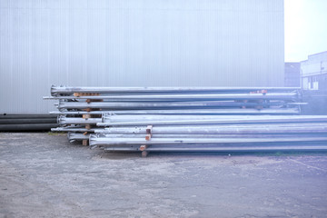 Metal warehouse indoor of lighting poles. Storage of metal galvanized faceted pipes with flange. ..
