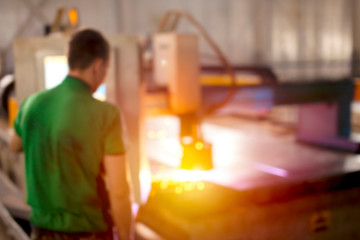 Plasma cutting machine operator. Professional worker at the plant. Metallurgical plant for the production of metal structures. Blurred.