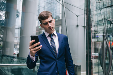 Businessman frowning looking at smartphone screen