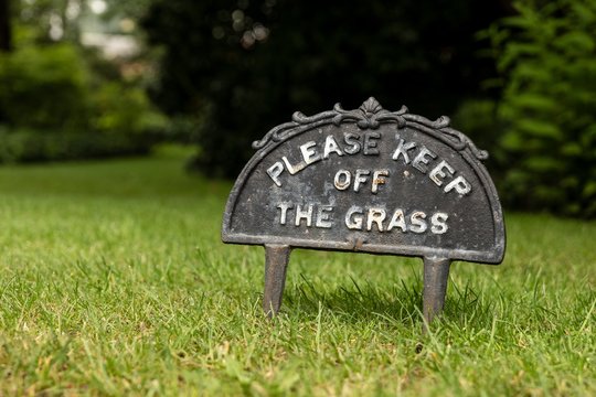 The small sign with a text Please keep off the grass to protect lawn