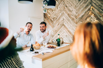 Cheerful men drinking champagne and toasting at Christmas