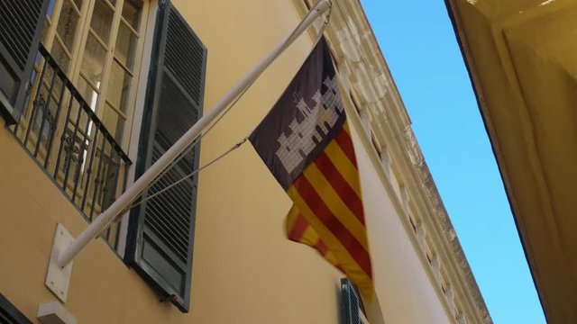 Catalonian Flag Waving on Flag Pole Attached to Building Under Window