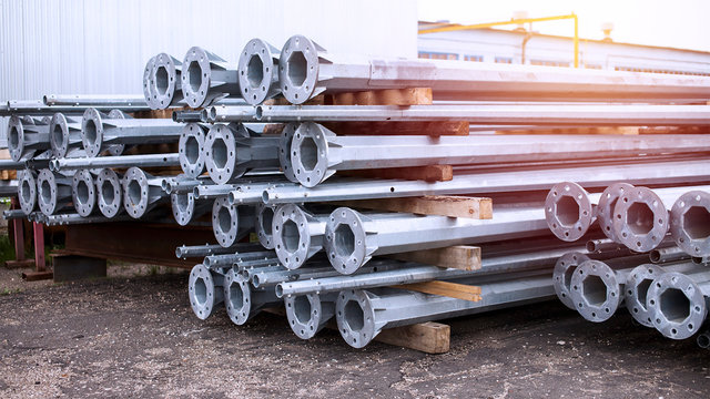 Metal warehouse indoor of lighting poles. Storage of metal galvanized faceted pipes with flange. ..