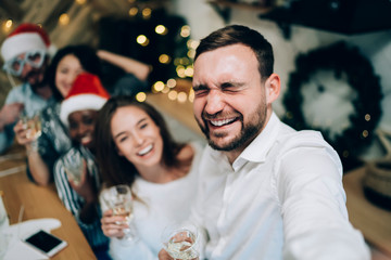 Handsome man laughing while taking selfie on Christmas party