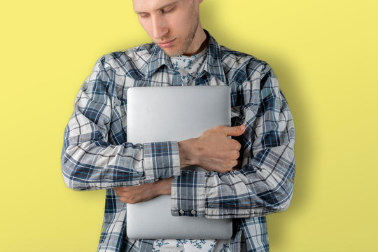 man holding and carrying the laptop, hug the cumputer standing against the color wall, education student