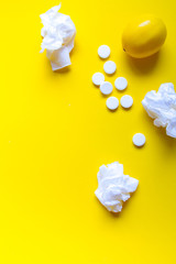 Fototapeta na wymiar Lemon, thermometer and white medical pills on yellow background, pharmacy theme, treatment and prevention of virus. Concept of health in season of colds.