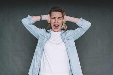 Woman screaming covering ears with hands in studio