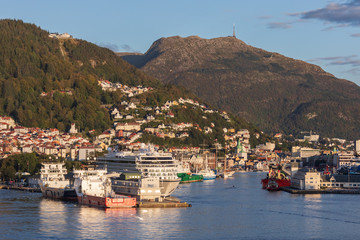 Fototapeta na wymiar Stadt und Hafen von Bergen in Norwegen mit den Bergen Fløyen und Ulriken. Im Hafen ein Kreuzfahrtschiff und Offshore-Versorgungsschiffe.