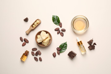 Fototapeta na wymiar Organic cocoa butter, beans and essential oil on beige background, flat lay