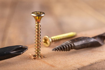 Hand drill, screws and screwdriver for small carpentry work. Carpentry tools on a workshop table.
