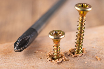 Screwdriver and screws for connecting wooden elements. Carpentry tools on a workshop table.