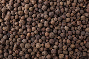 Black pepper grains as background, top view