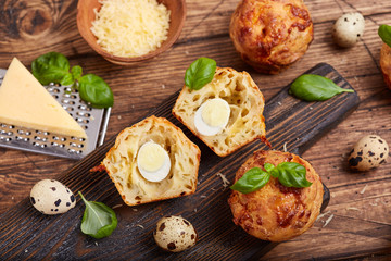 Savory muffins with cheese, quail egg and basil leaves. Delicious homemade appetizer. 