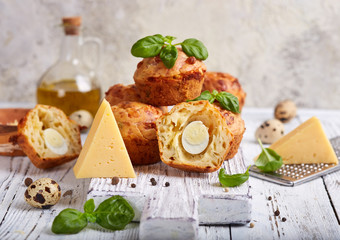 Savory muffins with cheese, quail egg and basil leaves. Delicious homemade appetizer. 