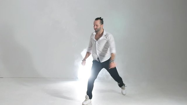 Professional male hip hopper in motion standing on light coloured floor of spacious dance hall, enjoying hip hop dance