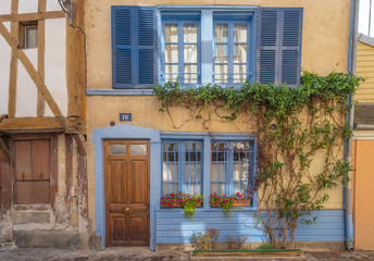 Troyes, France - 09 08 2019: Facade of a blue and yellow house with plants and climbers