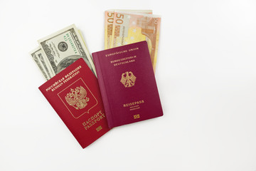 Official German and Russian passports with american dollars an euro banknotes on white background