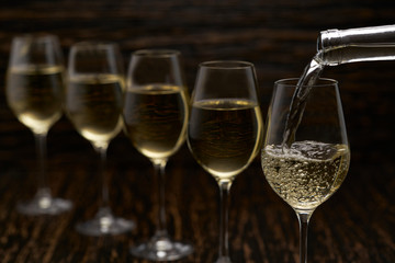 white wine pouring into glasses from bottle, selective focus