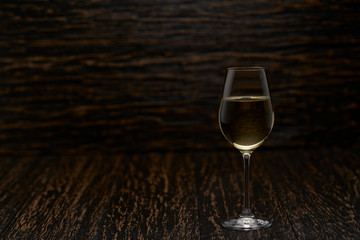 Full glass of  white wine on a black wooden background, with copy space.