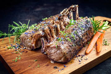 Gegrilltes Lamm Karree mit Karotten und Kräutern angeboten als closeup auf einem  Modern Design...