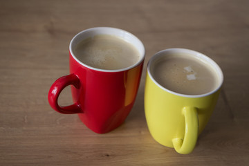 Two cups of cappuccino with latte art on wooden background. Beautiful foam, greenery ceramic cups, stylish toning, place for text.