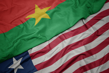 waving colorful flag of liberia and national flag of burkina faso.