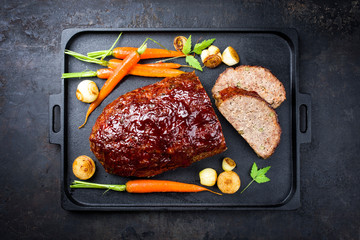 Traditional American meatloaf with ketchup from ground beef with carrots and onion as top view on a...