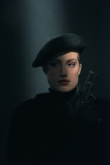 Retro 1940s woman in beret holding pistol.