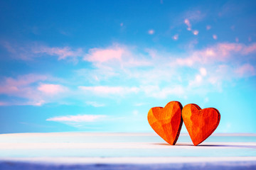 Two bright shining red wooden hearts against the backdrop of romantic heaven. Valentines day or...