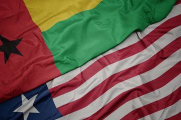 waving colorful flag of liberia and national flag of guinea bissau.